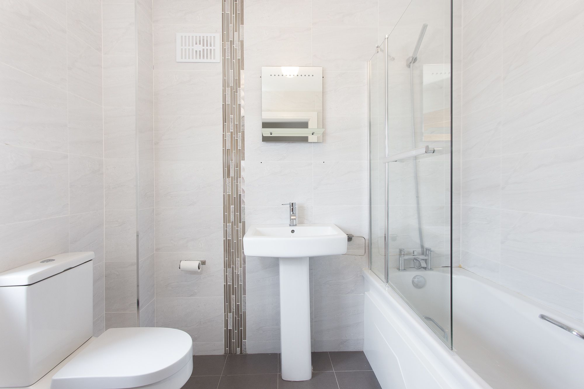 Un baño moderno con inodoro, lavamanos y ducha.