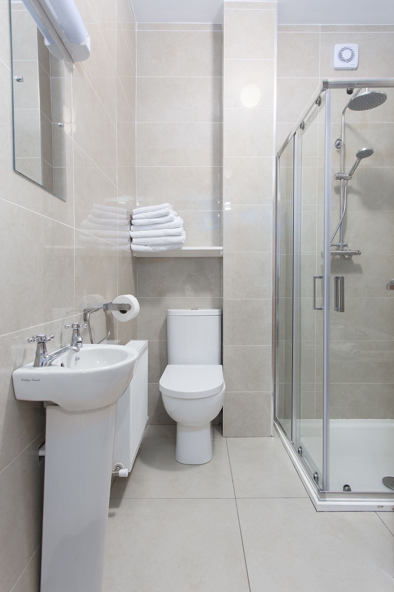 A modern bathroom with a glass-enclosed shower, a white sink, and a toilet.