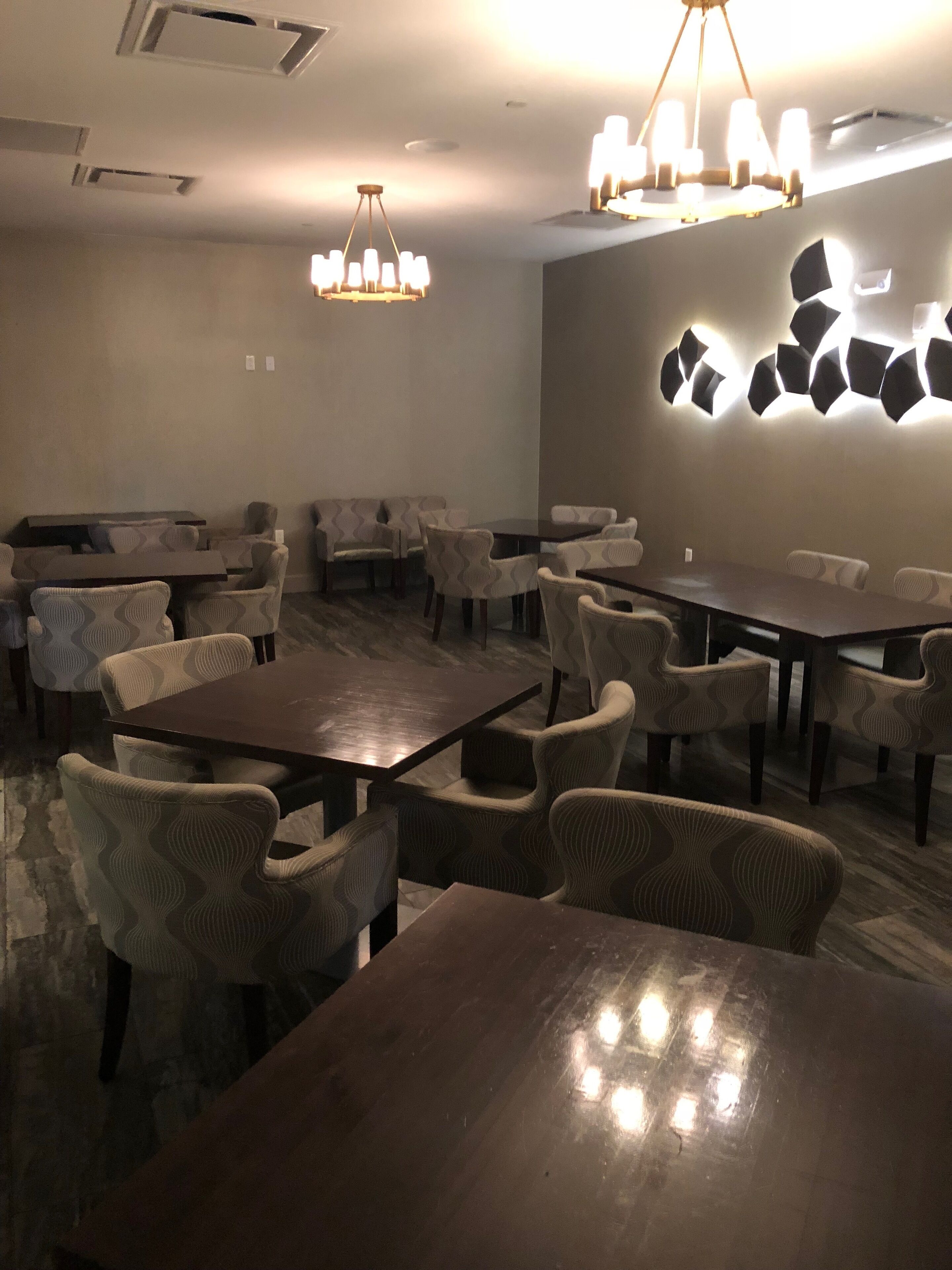 Un salón de conferencias con varias mesas y sillas, una araña de cristal y una lámpara de pared.