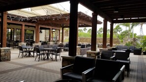 An outdoor patio area with stone pillars, black wicker furniture, and string lights. - Embassy Suites by Hilton McAllen Convention Center (McAllen)