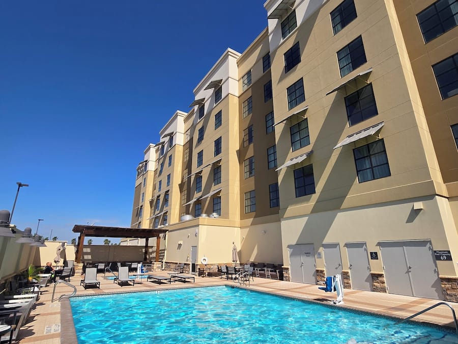A hotel with a swimming pool, outdoor seating, and multiple floors.