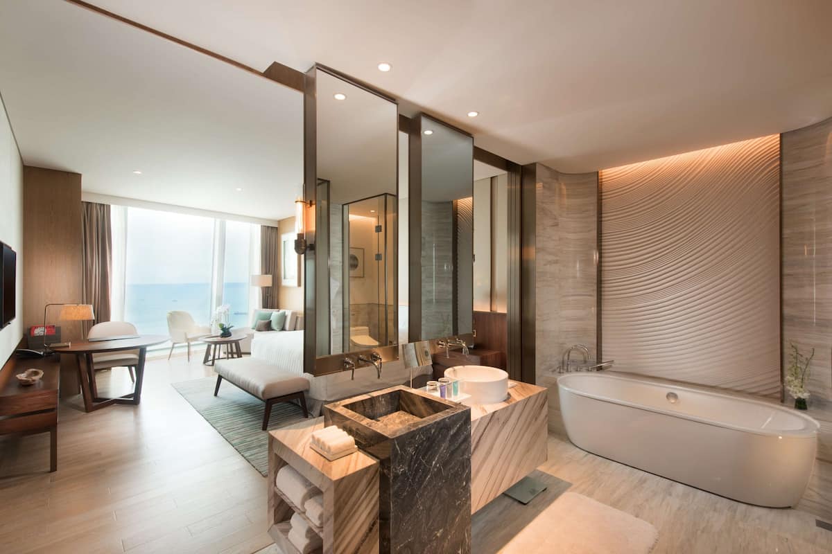 A modern bathroom with a large bathtub, a vanity with a marble countertop, and a large mirror.