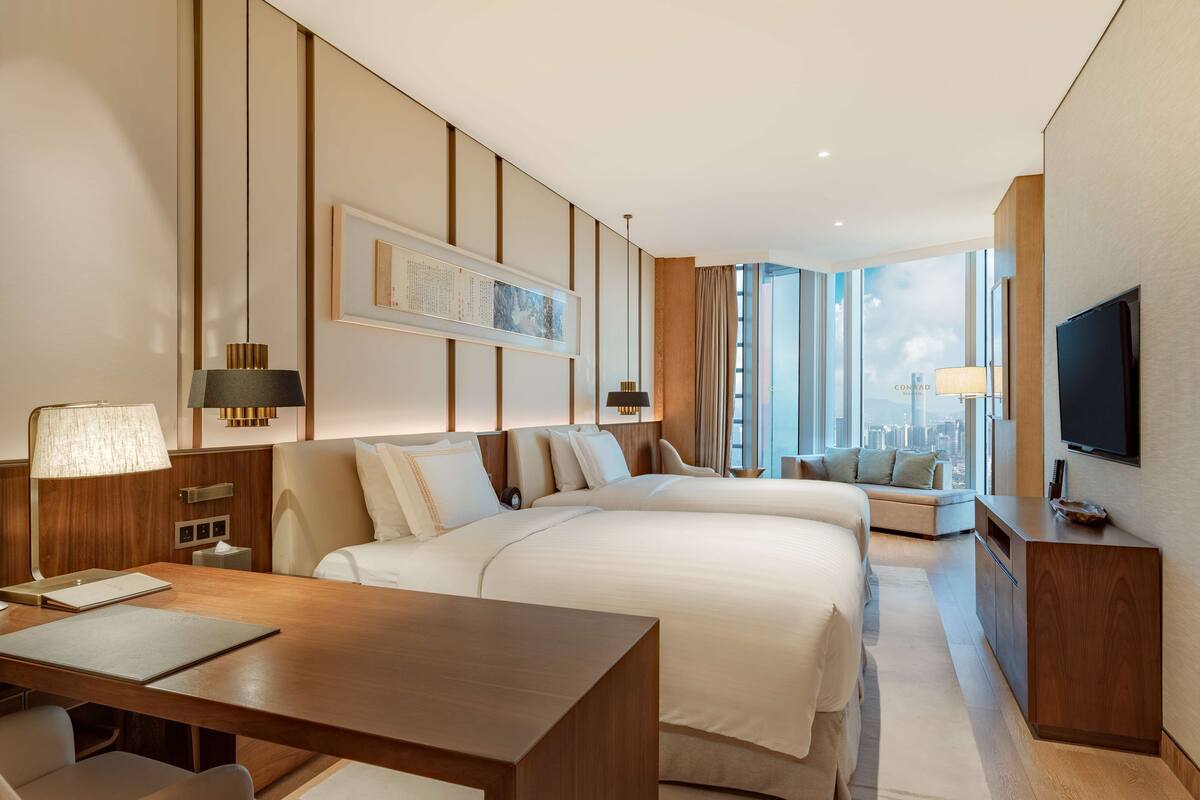 A modern hotel room with a large bed, a desk, and a TV.