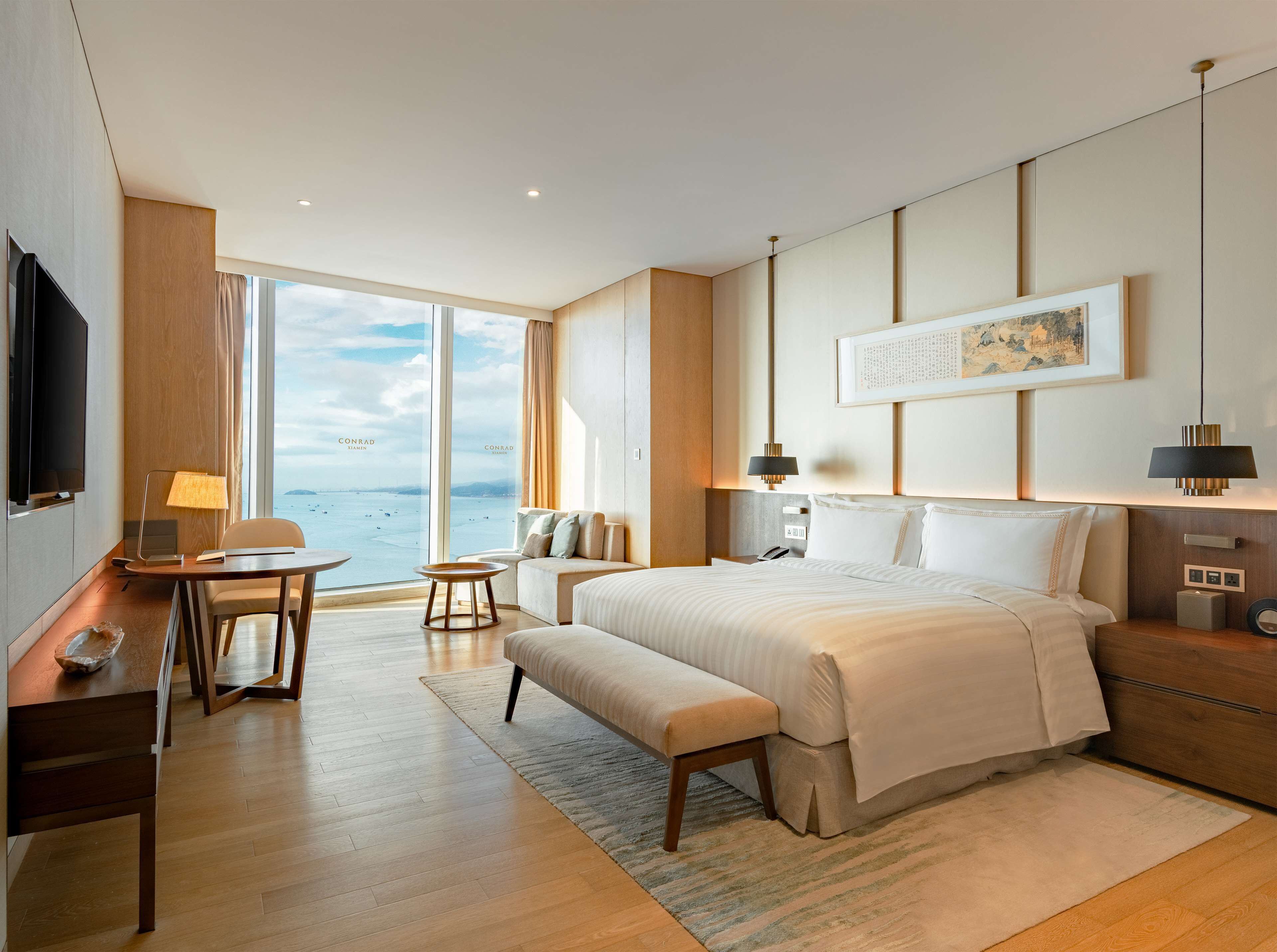 Una habitación de hotel moderna con una cama grande, un escritorio, una silla y vistas al mar.