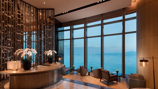 A modern lobby with a reception desk, seating area, and large windows offering a view of the sea. - Conrad Xiamen (Xiamen)