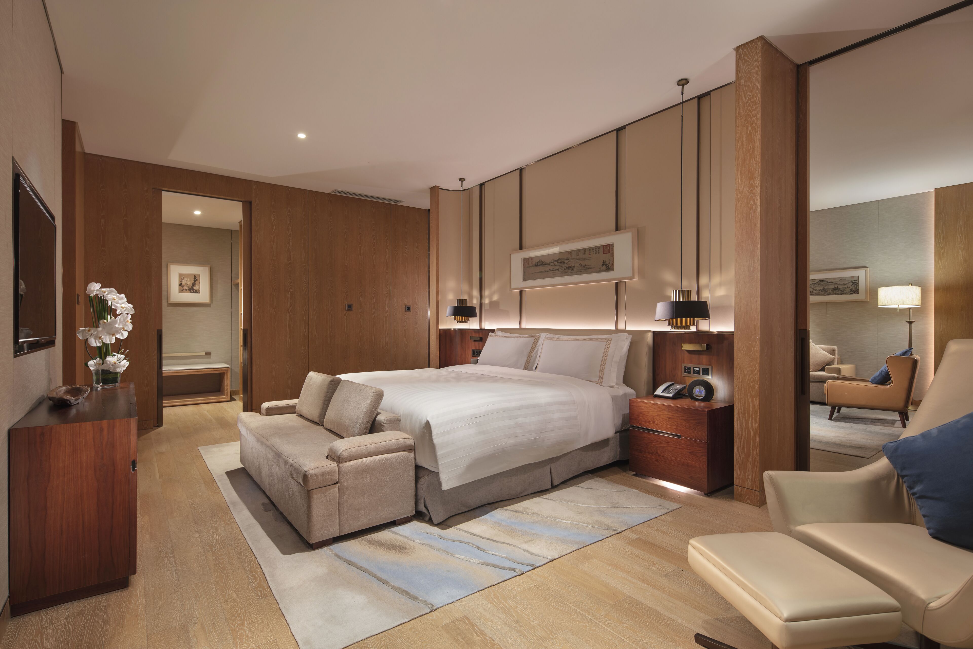 A modern bedroom with a large bed, a sofa, a desk, and a chair.