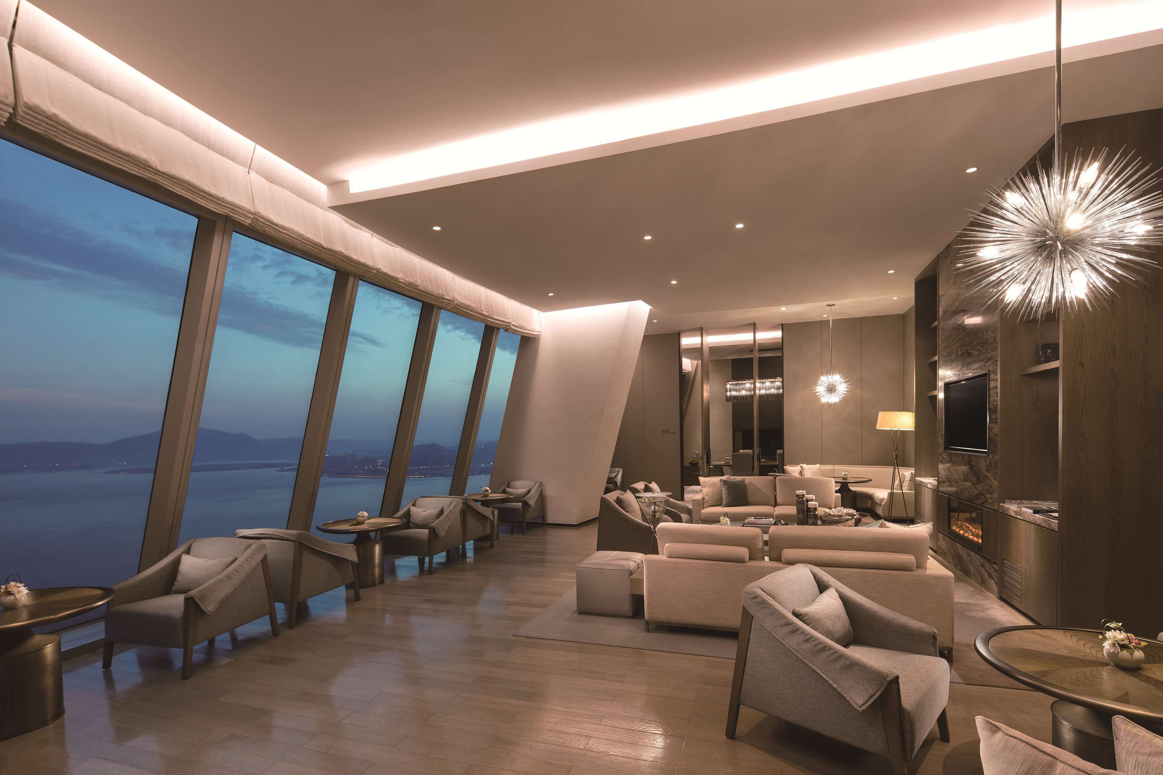 Una sala de estar moderna con ventanas amplias, chimenea y muebles contemporáneos.