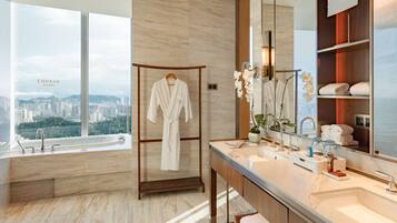 A modern bathroom with a large window, a bathtub, a vanity with a mirror, and a robe rack.