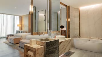 A modern hotel bathroom with a large mirror, a bathtub, a vanity with a marble countertop, and a large window with curtains.