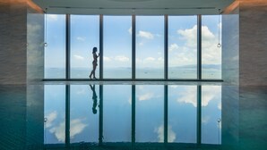 A large indoor swimming pool with a clear view of the sky and clouds through tall windows. - Conrad Xiamen (Xiamen)