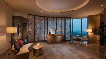 A modern lobby with a reception desk, seating area, and large windows offering a city view.