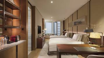 Habitación de hotel con una cama grande, un escritorio, un sofá, un televisor y vistas a la ciudad.