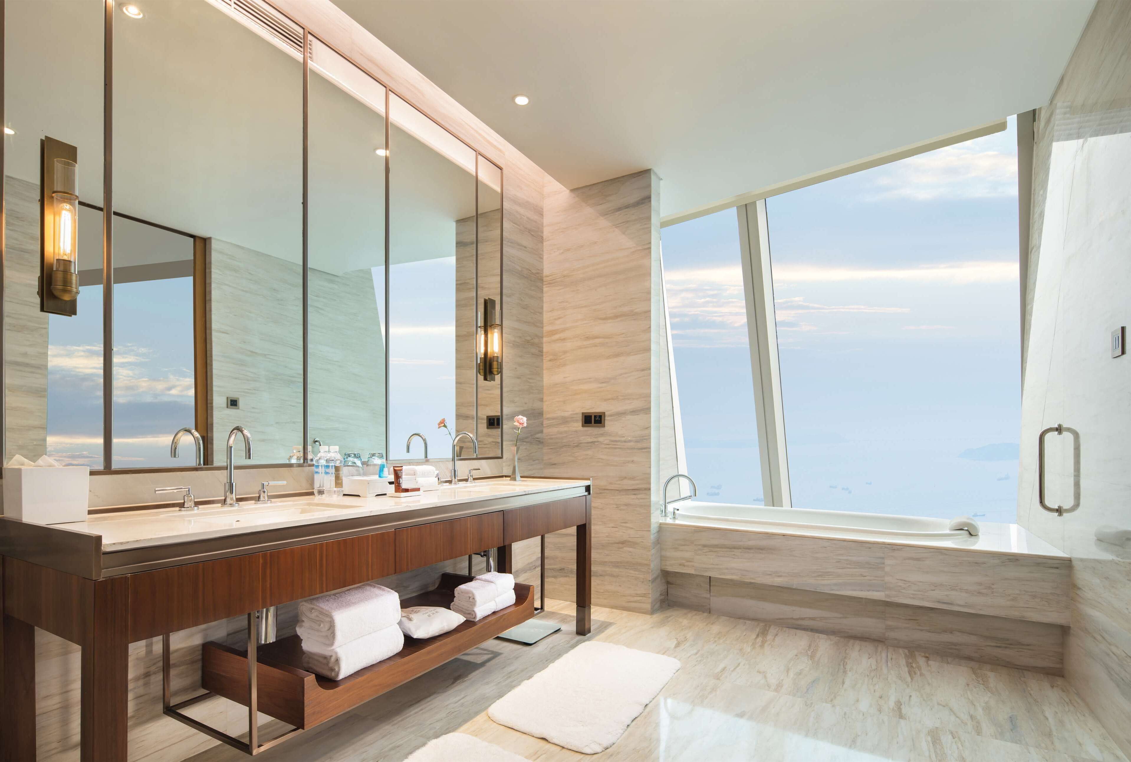 Un baño moderno con un espejo grande, lavamanos dobles, tocador y bañera.