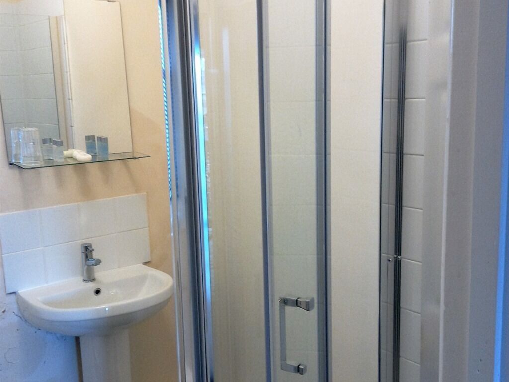 A bathroom with a white sink, a mirror, and a glass shower enclosure.