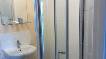 A bathroom with a white sink, a mirror, and a glass shower enclosure.