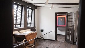 A room with a wooden desk, a chair, a window with a metal grille, and a door with a decorative panel. - Hotel Bamberger Hof (Wutha-Farnroda)
