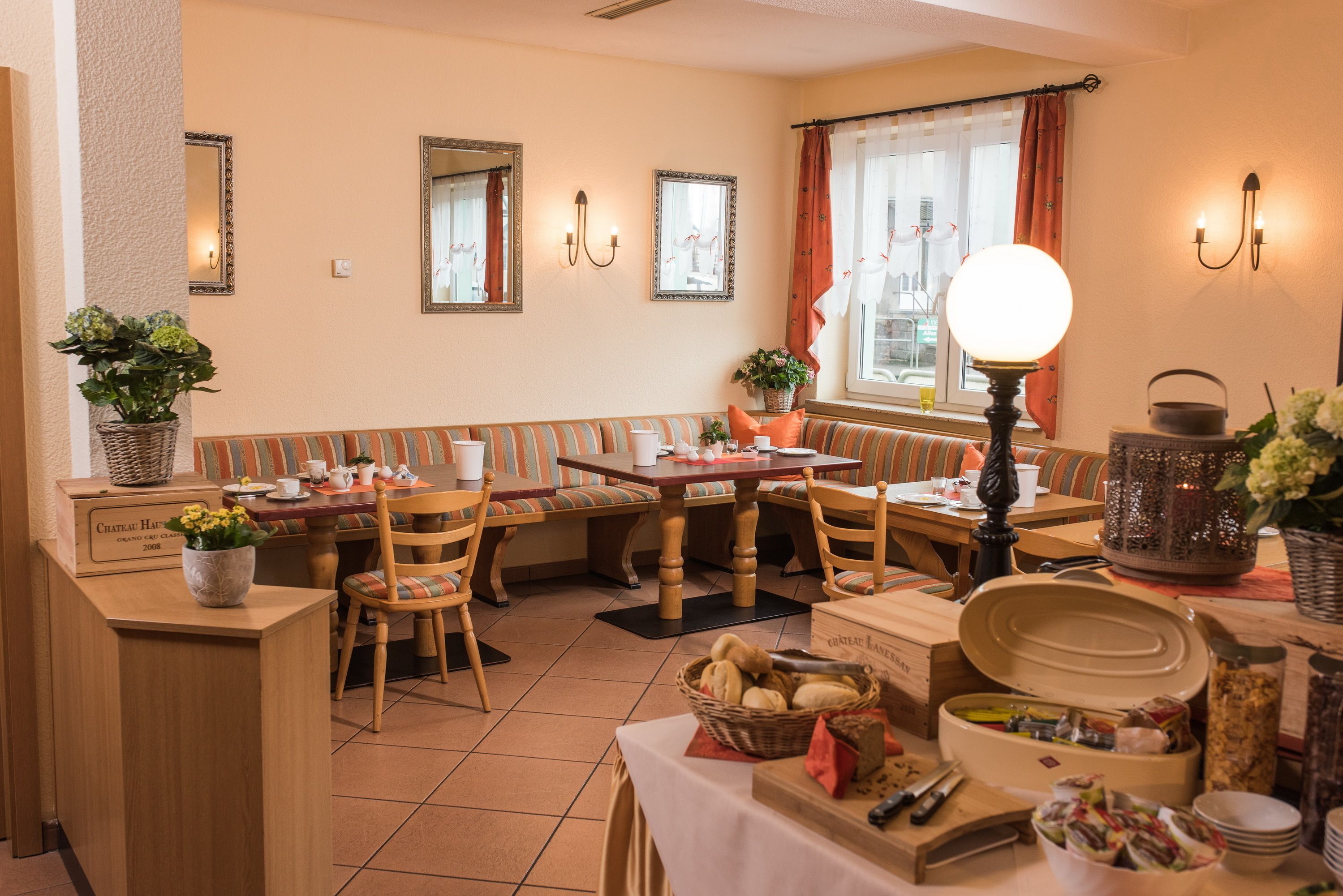 A cozy dining area with wooden furniture, a table set for a meal, and a window with curtains.