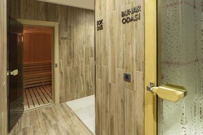 Un pasillo de hotel con paneles de madera, una puerta de ascensor de vidrio y una puerta de madera con la etiqueta 'BUHARA ODSI'.