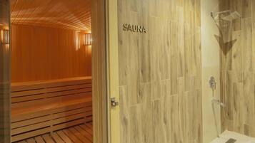 Een sauna met houten banken en een houten wand waarop ‘SAUNA’ staat.