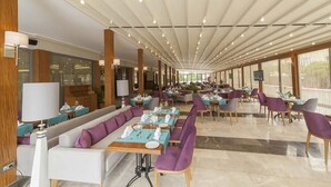 A spacious hotel lobby with a long dining area, multiple seating options, and large windows providing natural light. - Lamec Hotel Business (Gebze)