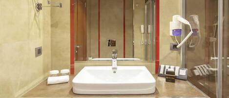 A modern bathroom with a large sink, mirror, and glass shower enclosure.