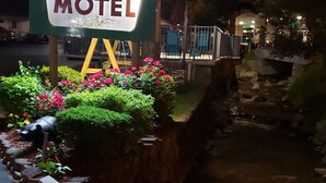 Une enseigne indiquant le « Marshalls Creek Rest Motel », avec un petit ruisseau et des fleurs au premier plan.