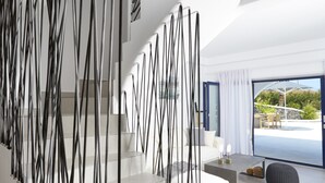Un interior moderno con una escalera, arte abstracto en la pared y vistas al exterior.