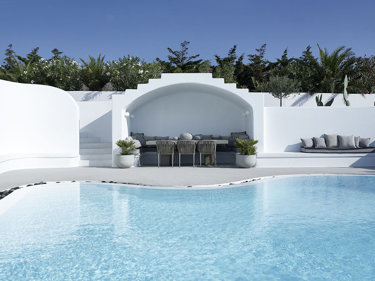 A modern pool area with a built-in seating area and a staircase leading to a roofed terrace.