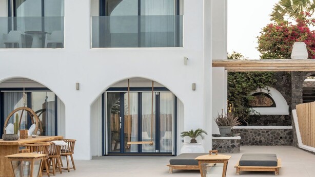 Una casa moderna con piscina, mobiliario de exterior y un muro de piedra.