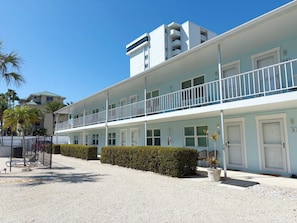 A multi-story hotel with a light blue facade, multiple balconies, and a gravel driveway. - Gulf Holiday by Beachside Management (Siesta Key)