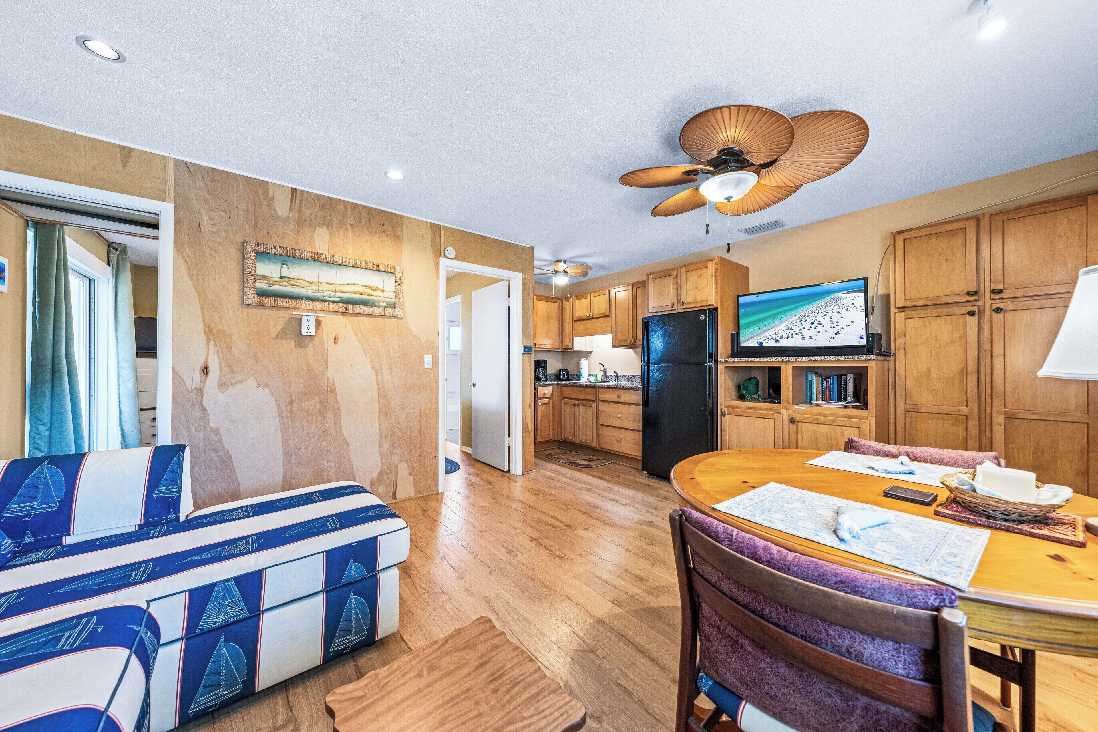 A modern kitchen with wooden cabinets, a black refrigerator, and a television.