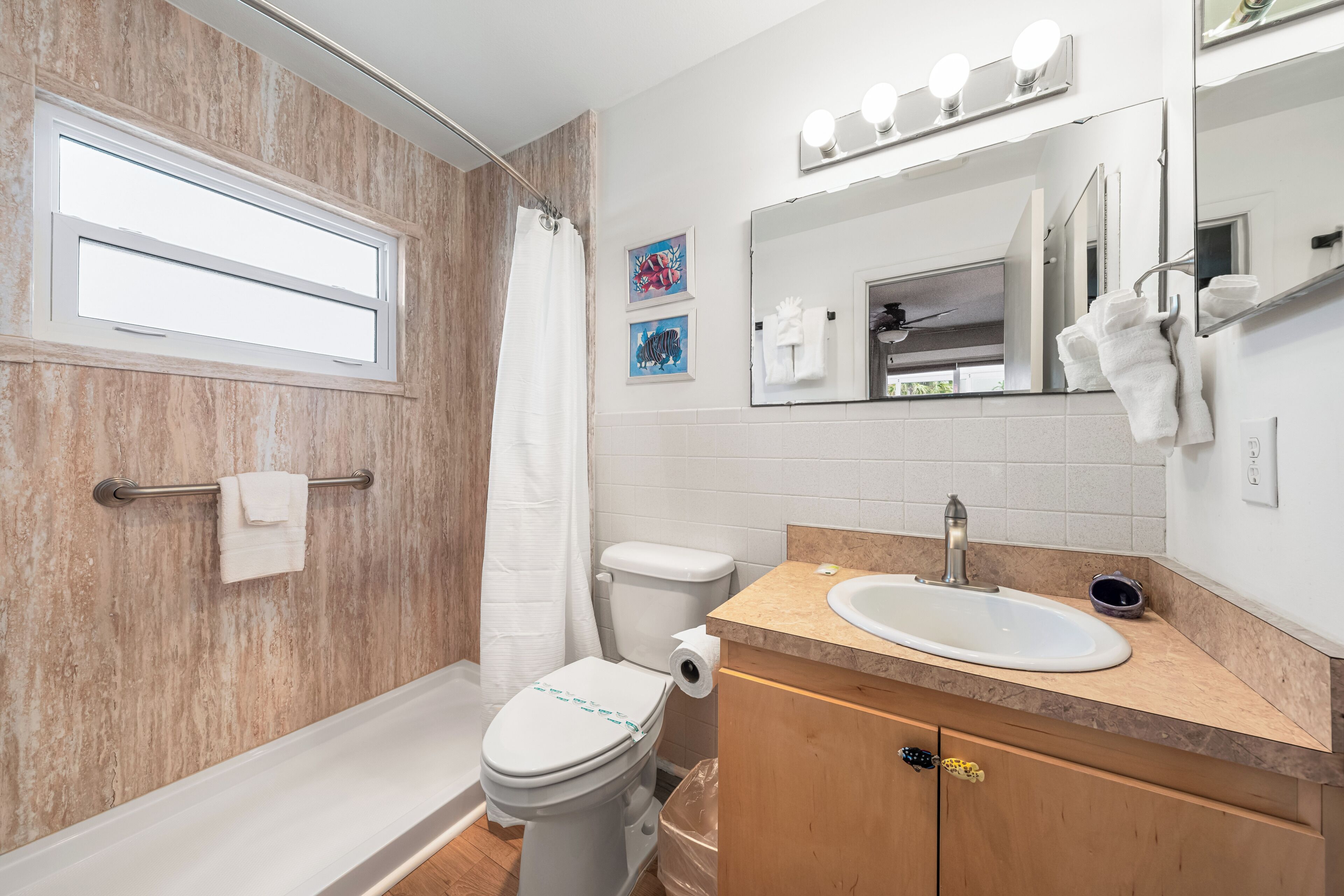 A bathroom with a shower, toilet, sink, and vanity.