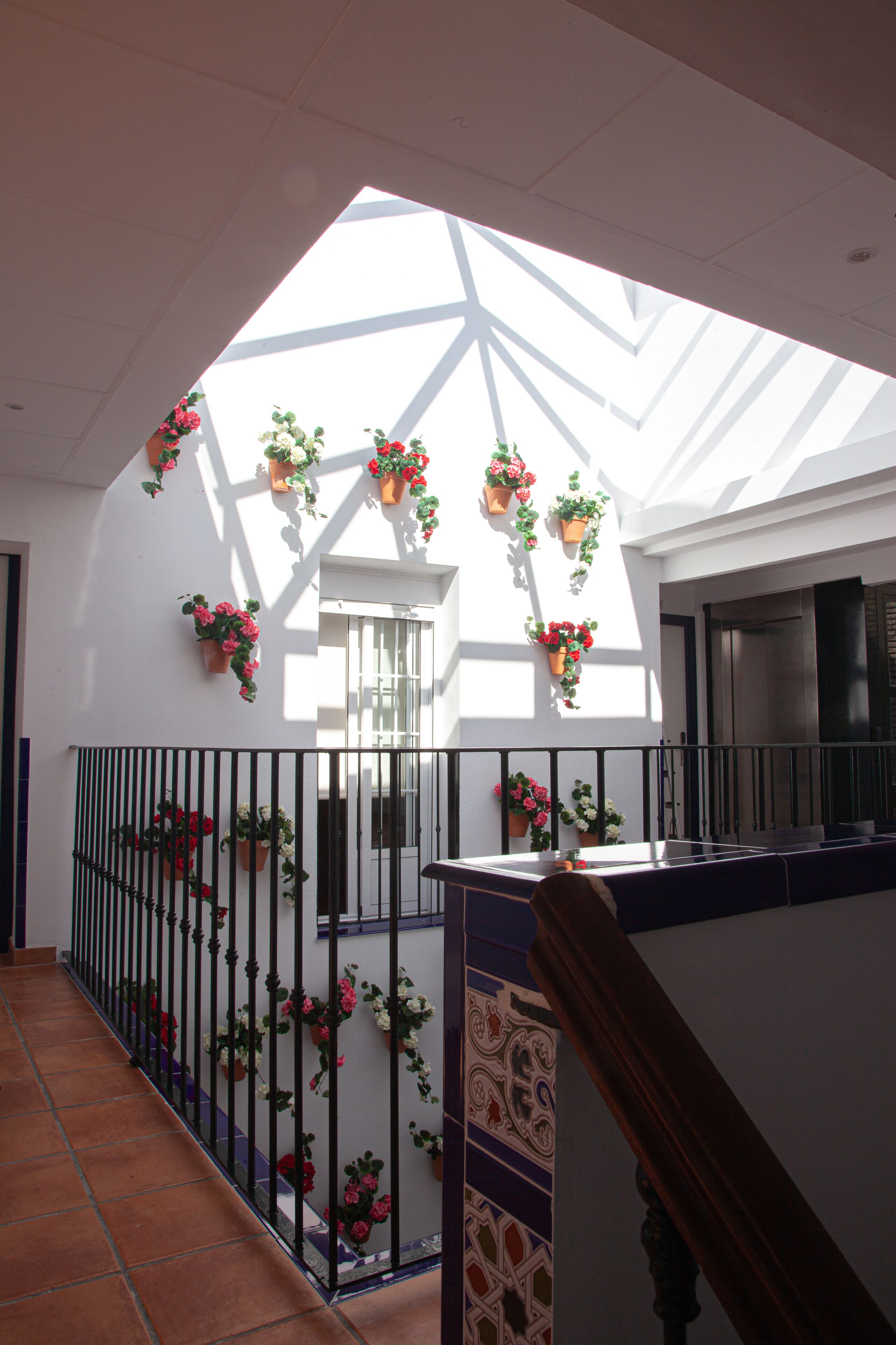 A covered outdoor area with a tiled floor, a staircase, and potted plants.