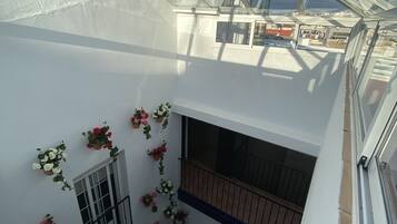 Un interior de varios niveles con techo de vidrio, balcones y plantas en macetas.