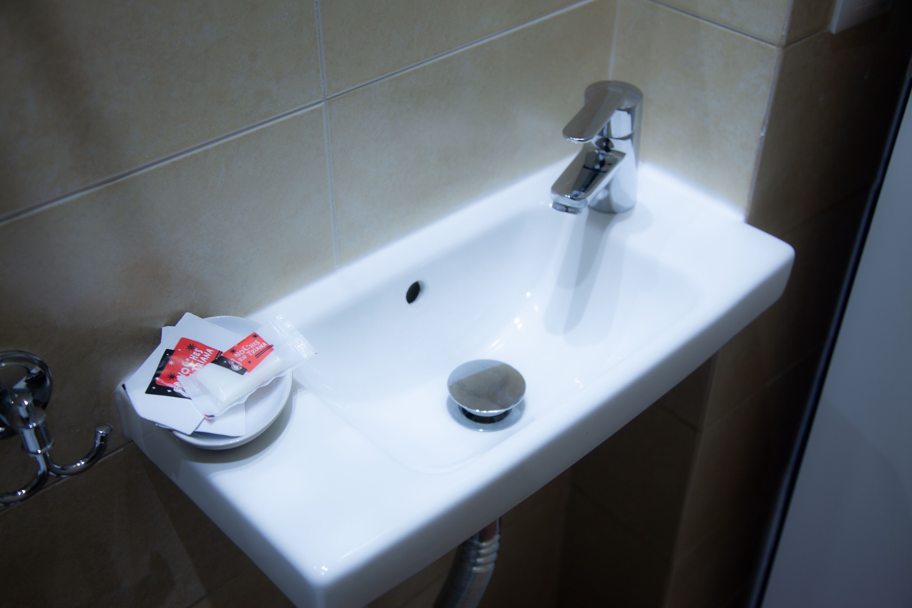 A white bathroom sink with a chrome faucet and a soap dispenser.