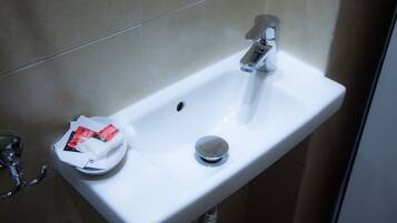 A white bathroom sink with a chrome faucet and a soap dispenser.