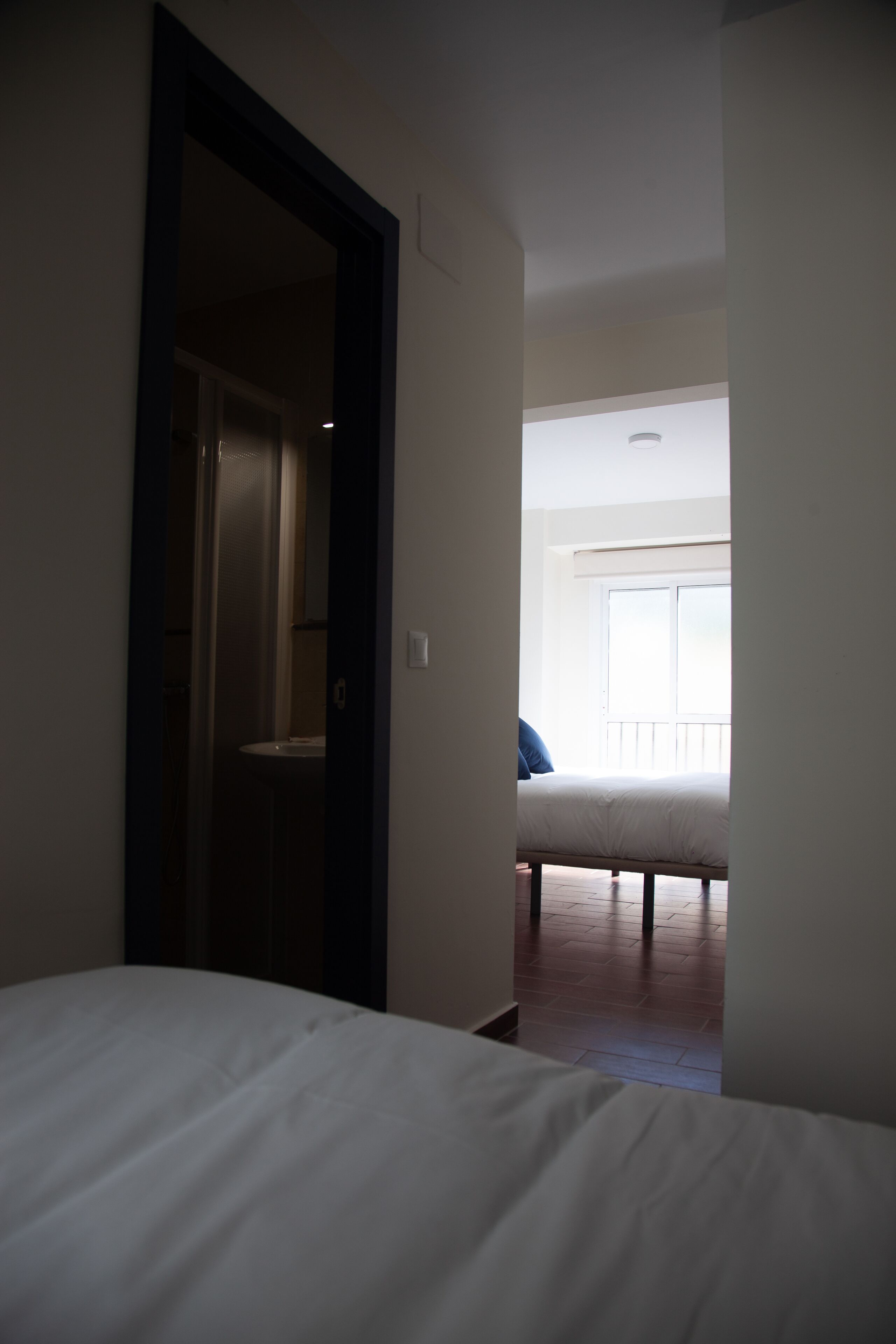 Habitación de hotel con cama, puerta que da a un baño y ventana con vistas al exterior.