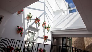 A building with white walls, multiple hanging flower planters, and a balcony railing.