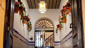 A hallway with patterned tile flooring, a decorative ceiling light, and potted flowers on the walls.