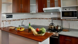 A kitchen with wooden cabinets, a microwave, a stove, and a fruit bowl on the counter. - Polo Apartment (Cusco)