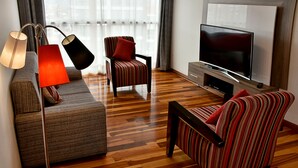 A modern living room with a sofa, striped armchairs, a TV, and a lamp. - Polo Apartment (Cusco)