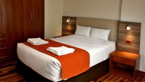 A hotel room with a large bed, wooden wardrobe, and bedside tables with lamps. - Polo Apartment (Cusco)