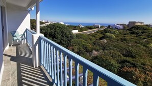 Een balkon met uitzicht op de oceaan en de omliggende begroeiing.