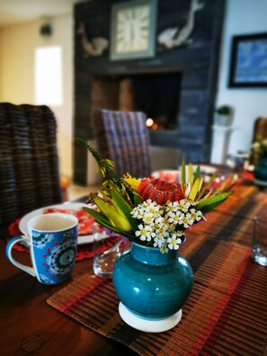 Ein Esstisch mit floraler Dekoration, einer blauen Tasse und einer karierten Tischmatte.