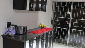 Een keukentafel met een waterkoker, broodrooster en een schaal fruit.