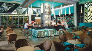 Un restaurant doté d'un bar, de meubles en osier et d'une décoration aux tons turquoise.