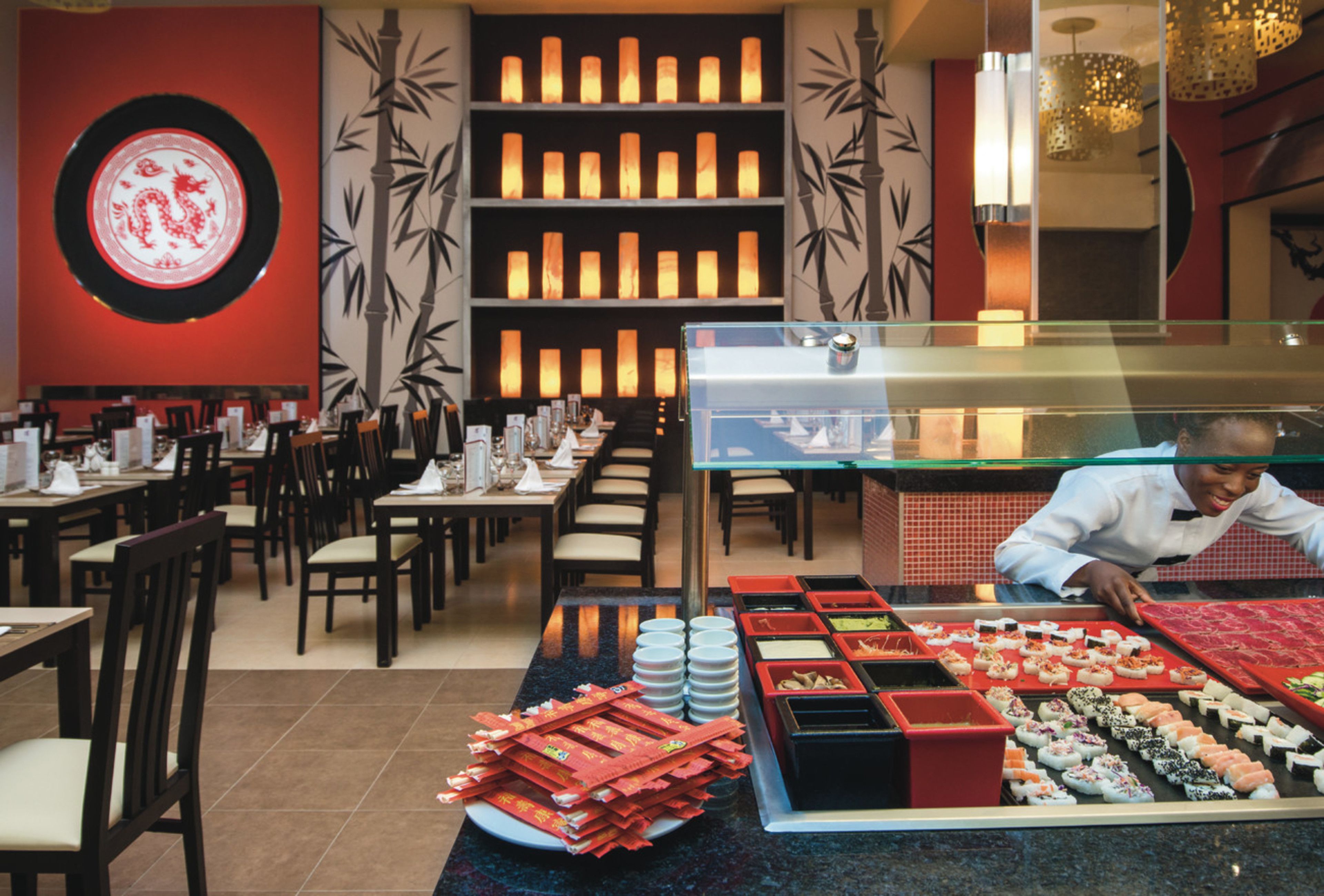 A sushi bar with various types of sushi displayed in front of a chef.