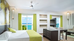 Une chambre d’hôtel avec un lit, un bureau, une chaise, une télévision et une vue sur l’océan.