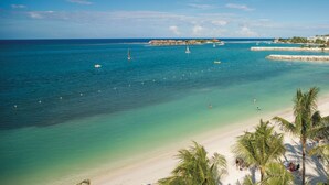 Une plage à l’eau turquoise et limpide, bordée d’un rivage sablonneux et de palmiers.