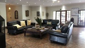 A spacious lobby with leather sofas, a coffee table, and a chandelier. - St Ives Lodge (Lidgetton West)